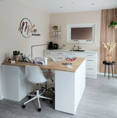 a kitchen area with a desk, chair and television mounted on the wall above it