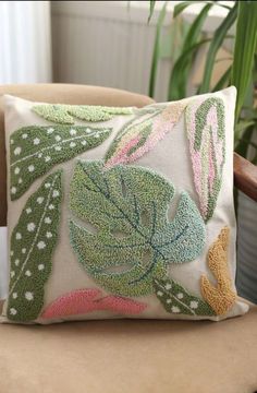 a decorative pillow on a chair in front of a potted plant and window sill