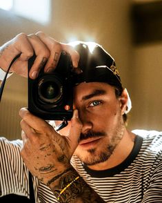 a man holding up a camera to take a selfie with his hat over his head