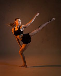 a woman in black is doing a dance pose with her leg up and legs spread out