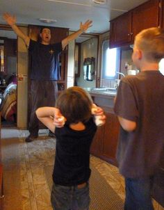 two young boys are playing video games in the living room with their arms raised up