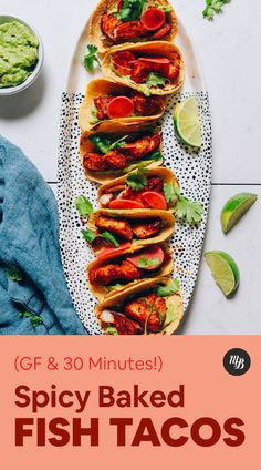 spicy baked fish tacos on a plate with guacamole and limes