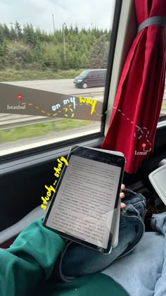 a person sitting in a bus with an electronic device on their lap and looking out the window