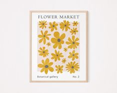 a yellow flower market poster hanging on a wall next to a wooden framed sign that says botanical gallery no 2