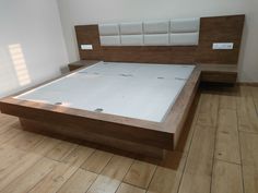 a large bed with wooden headboard and foot board in a room that has hard wood flooring