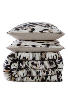 three pillows stacked on top of each other in front of a white background with black and brown spots