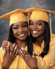 two women in graduation caps and gowns posing for the camera with their hands on each other's shoulders