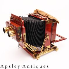 an old fashioned camera sitting on top of a white surface with the words apsley antiques written below it