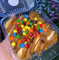 a plastic container filled with lots of candy and pretzel toppings on top of it