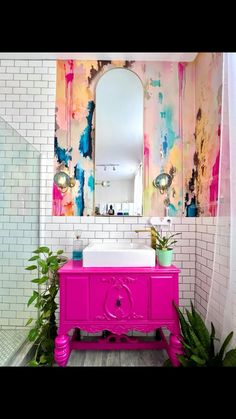 a bathroom with a pink vanity, mirror and plants in front of the sink area