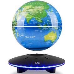 a small blue and green globe on top of a black stand with white background in front of it