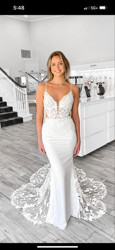 a woman in a white wedding dress standing on a wooden floor next to some stairs