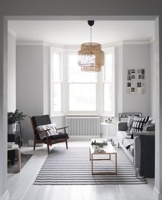 a living room filled with furniture and a rug on top of a hard wood floor