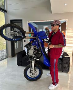 a man standing next to a blue dirt bike