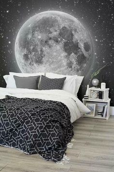 a bedroom with a full moon and stars on the wall behind it, along with a black and white bed spread