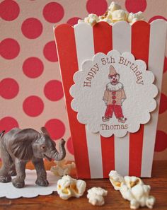 an elephant figurine next to a popcorn box with the words happy birthday thomas on it