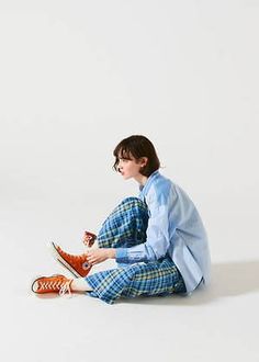 a woman is sitting on the floor with her feet crossed and holding a coffee cup