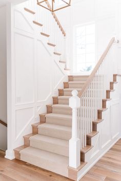 a white staircase with wooden handrails and beige carpet