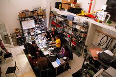 a group of people sitting around a table in a room with lots of clutter