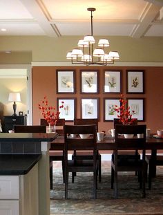 a dinning room table with chairs and pictures on the wall behind it in an open floor plan