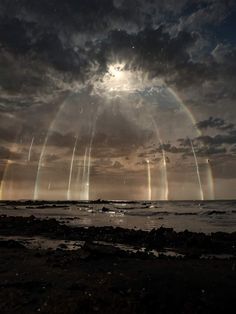 a group of jets flying over the ocean under a cloudy sky with rainbows in the background