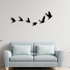 a living room with a blue couch and birds on the wall above it are three black birds