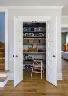 an open door leading into a room with wooden floors and white walls, filled with items