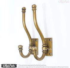 two brass colored metal hooks on a white wall