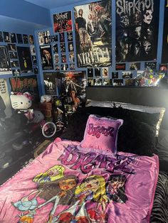 a bedroom with posters on the wall and a bed covered in a pink bedspread