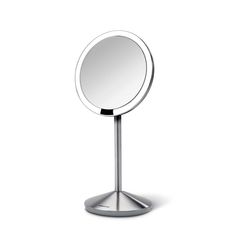 a round mirror sitting on top of a metal stand