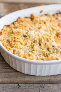 a casserole dish with cheese and other toppings in it on a wooden table