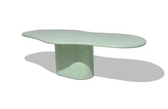 an oval shaped table sitting on top of a white floor next to a light green wall