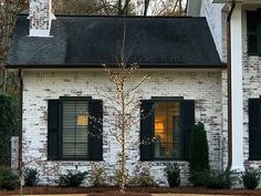 a white brick house with black shutters and trees