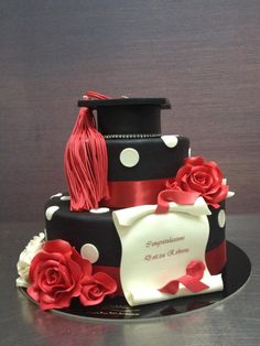 a black and white cake with red flowers on it, topped with a graduation cap