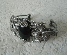 This beautiful silver plated filigree cuff bracelet has silver plated dragons, silver plated accents and a black onyx setting. Adjustable. Gothic Metal Jewelry With Dragon Design, Elegant Adjustable Dragon Design Jewelry, Elegant Adjustable Jewelry With Dragon Design, Handmade Gothic Metal Bracelets, Silver Fantasy Jewelry For Formal Occasions, Medieval Metal Bracelet Jewelry, Gothic Bangle Bracelet For Gift, Ornate Silver Hand Cast Jewelry, Gothic Antique Silver Jewelry With Intricate Design