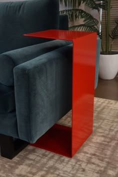 a blue couch sitting next to a red table on top of a carpeted floor