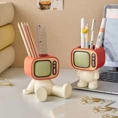 two little figures sitting on top of a desk next to a laptop