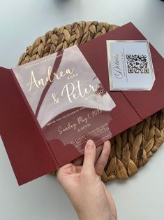 a person holding up a red wedding card in front of a basket with other items