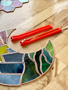 a stained glass sun catcher sitting on top of a wooden table next to scissors and glue