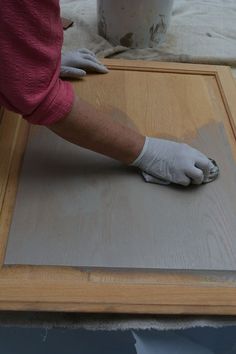 a person in white gloves is working on a piece of plywood board with cement