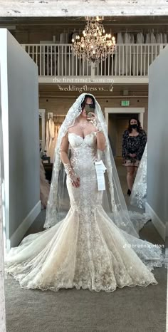 a woman in a wedding dress is taking a selfie with her cell phone while wearing a veil