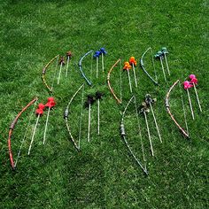 an array of arrows and bows laid out on the grass with red flowers in them