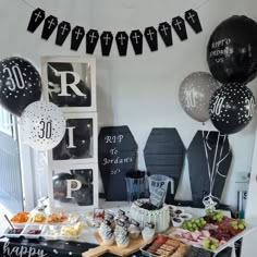 a table filled with lots of food and balloons in the air next to a clock