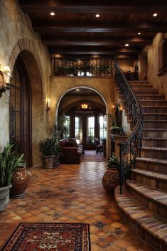 a large foyer with stairs, potted plants and rugs on the floor in front of it