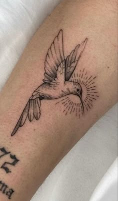 a small bird tattoo on the arm with an inscription in hebrew and sunburst