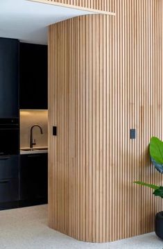 a modern kitchen with black cabinets and wood paneling on the walls, along with a potted plant