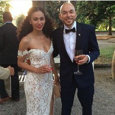 a man and woman standing next to each other holding wine glasses in front of them