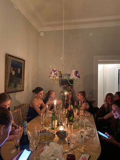 a group of people sitting around a table with wine bottles and candles in front of them