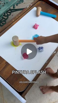 a child is painting on a table with paintbrushes and paper stars in front of them