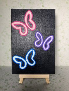 a painting on a wooden easel with butterfly shapes painted on it's side